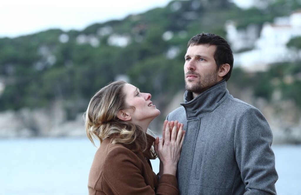 Woman pleading with man on a beach, he is ignoring her