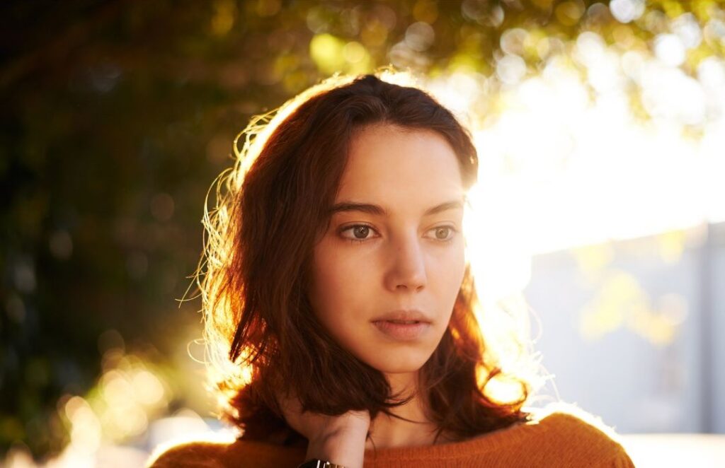 Woman looking unsure outside by tree